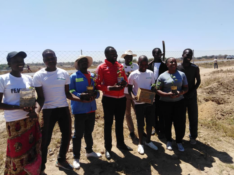 The Peace Building Committee pose for a photo before planting trees to commemorate the International Day of Peace  in Hopley on 21 September 2019 (right: Youth planting a tree.